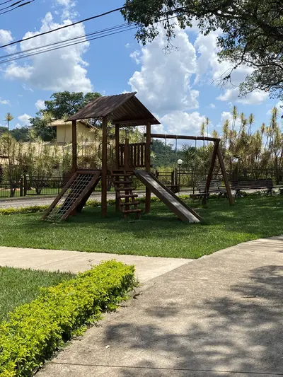 Playground com brinquedos de madeira e caminhos arborizados