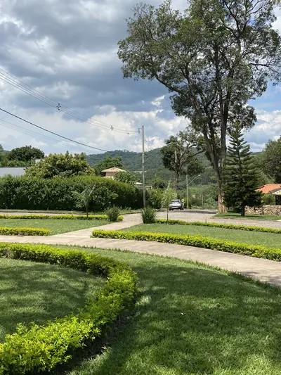 Jardins paisagísticos com cercas vivas e colinas ao fundo